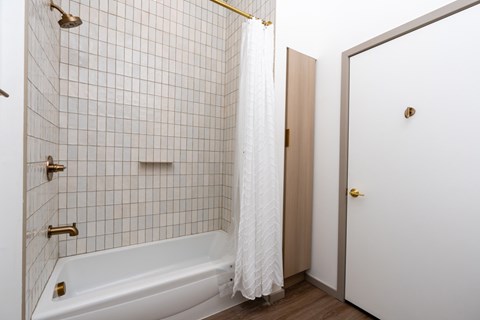 A white bathroom with a white tub and a white shower curtain.