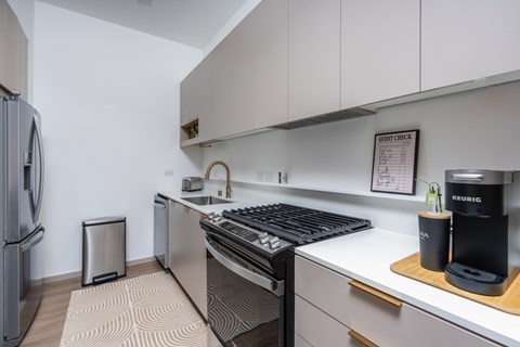 A modern kitchen with a black stove top oven and a white counter top.