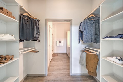 a walk in closet with shelves and a door to the bathroom