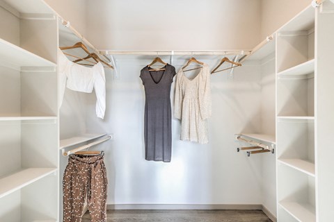 a walk in closet filled with dresses and hangers