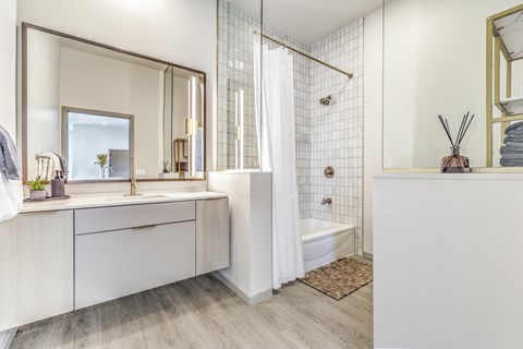 a white bathroom with a shower and a sink and a mirror