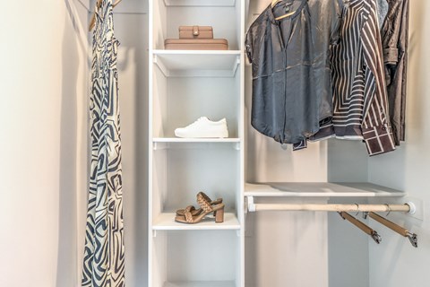 a walk in closet with shelves with clothes and shoes