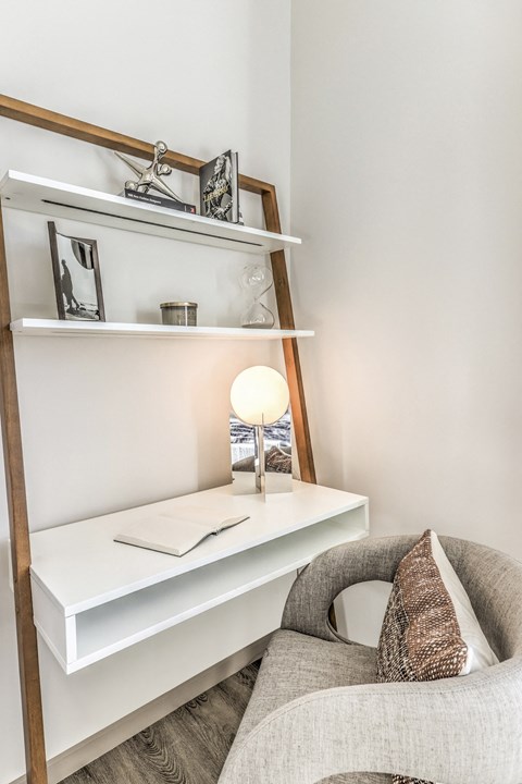 a white shelf with a lamp and a chair in a room
