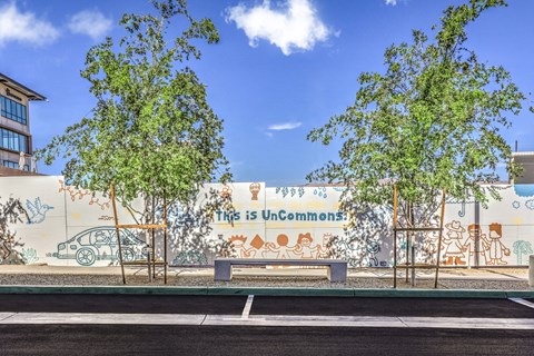 mural on the street with a bench and trees