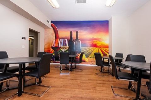 a room with tables and chairs and a mural of wine bottles and glasses on the wall at 55+ FountainGlen Temecula, Temecula, California