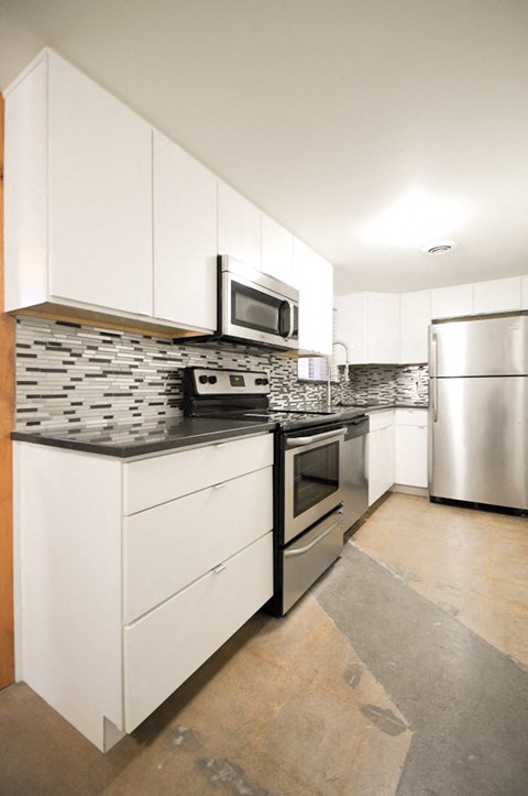 a kitchen with white cabinets and stainless steel appliances