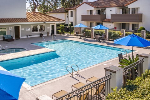 Resort style pool with spa and blue umbrellas at Woodbend Apartments, Alta Loma