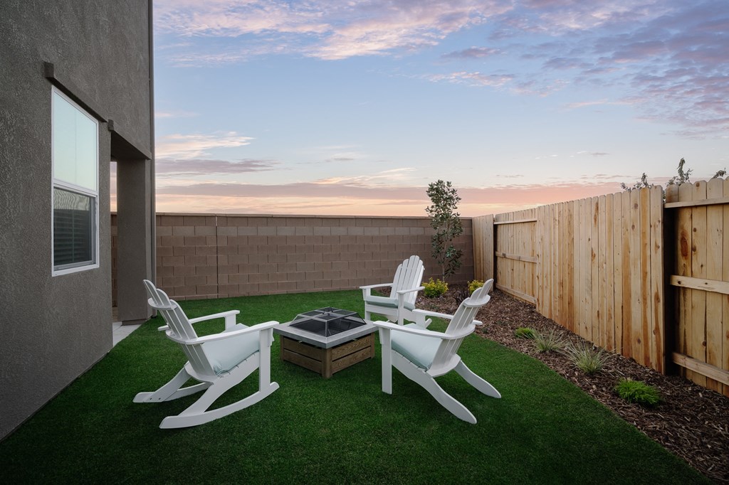 exterior of cyrene at fiddyment model home backyard with green lawn and firepit with 3 outdoor chairs