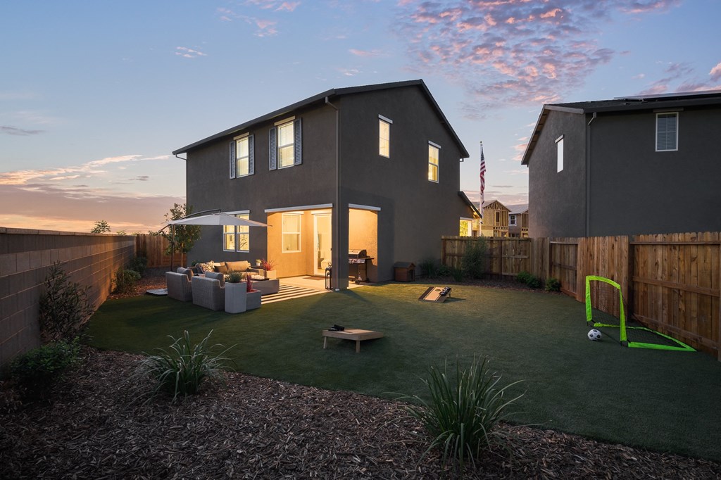 cyrene at fiddyment model home backyard with green lawn space and corn hole