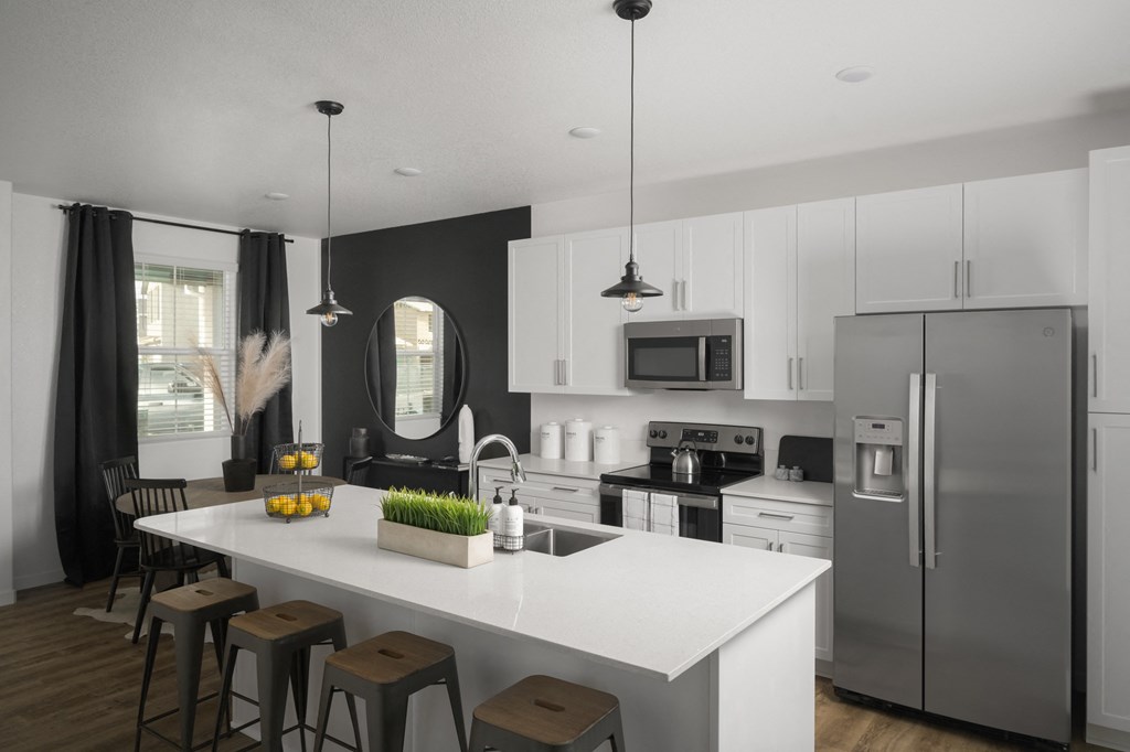 Roseville CA Homes - Cyrene at Fiddyment - Kitchen with White Countertops, White Cabinets, Island with Sink and Barstools, and Stainless Steal Appliances.