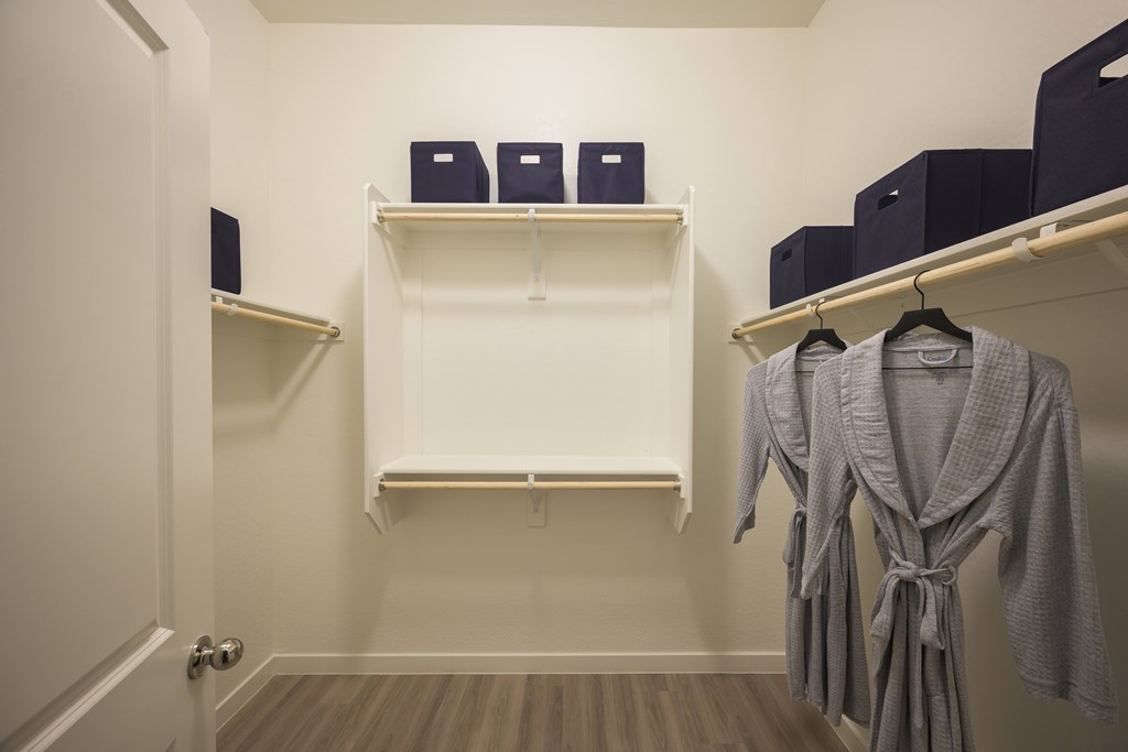 A white closet with a grey robe hanging on the right.