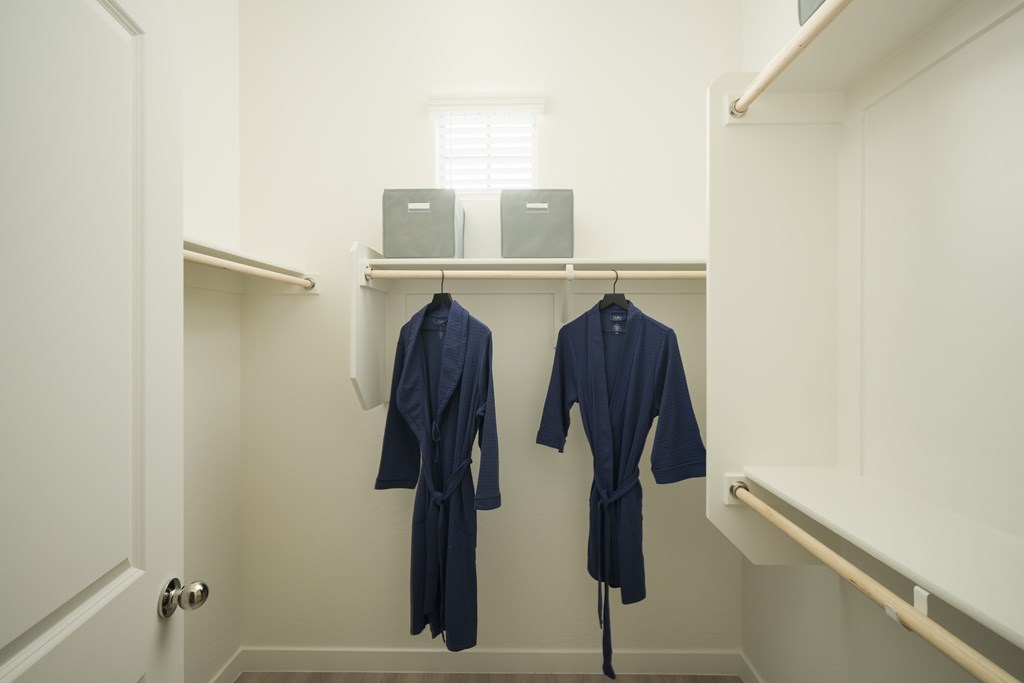 Two blue robes hanging on a rack in a white room.