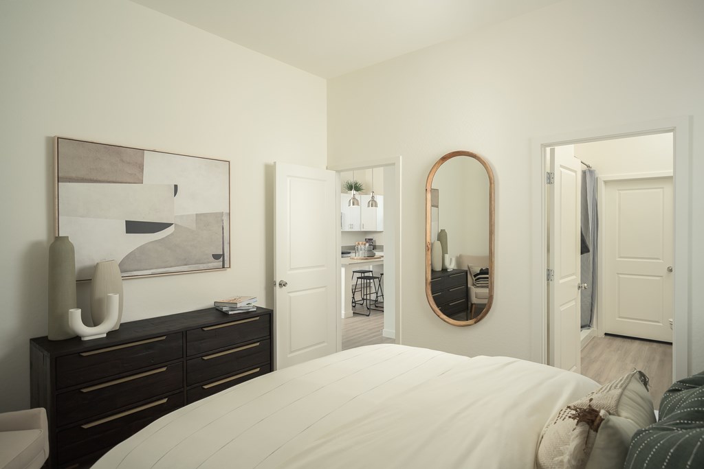 A bedroom with a large bed and a mirror on the wall.