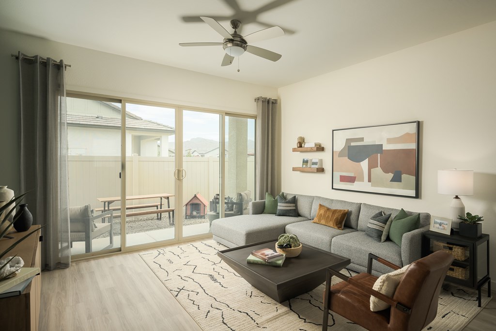 A living room with a grey couch, a coffee table, a ceiling fan, and a painting on the wall.
