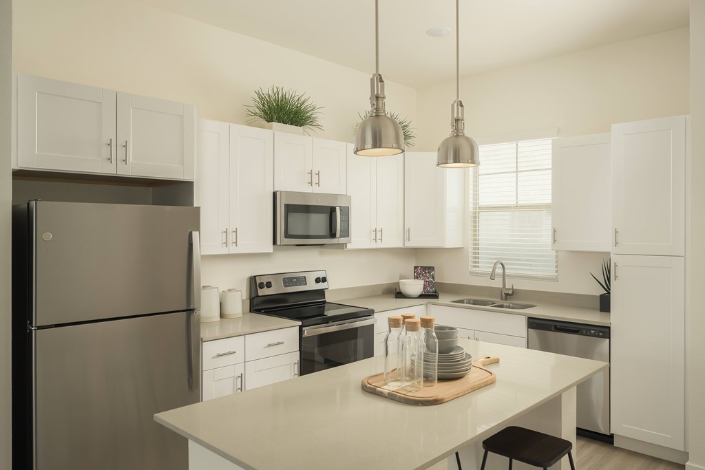 A modern kitchen with a refrigerator, microwave, oven, and sink.