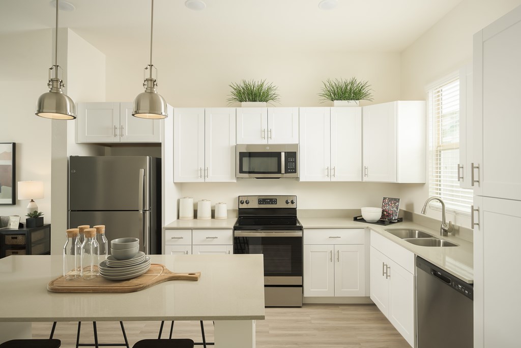 A modern kitchen with white cabinets and a wooden cutting board on the island.
