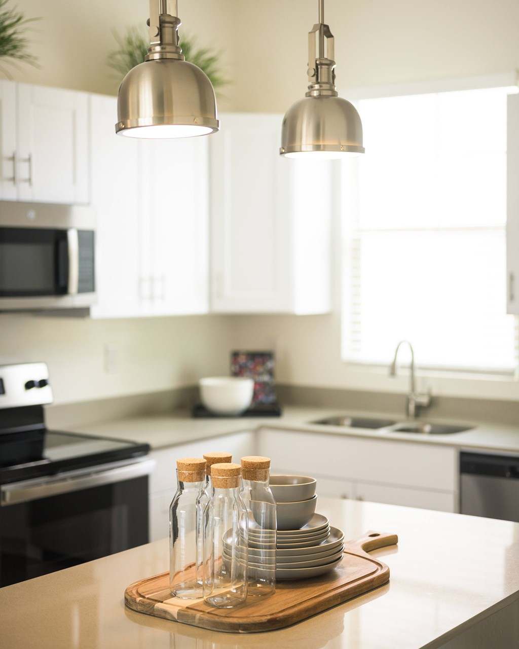 A kitchen with a wooden cutting board on the counter.