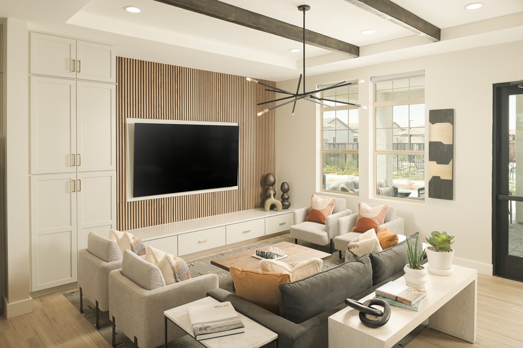 A modern living room with a grey sofa, a white coffee table, and a flat screen TV mounted on a wooden wall.