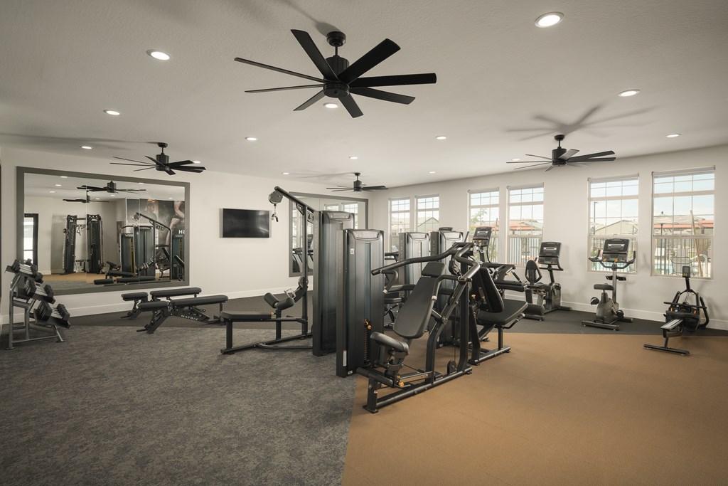 A spacious gym with a variety of equipment and a mirrored wall.