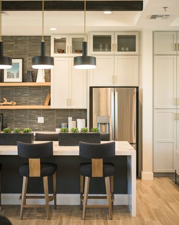 A kitchen with a white countertop and black bar stools.
