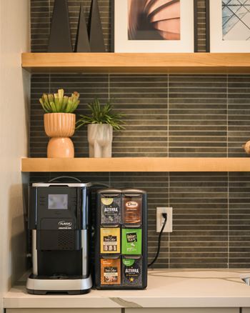 A coffee maker and a box of tea sit on a shelf.