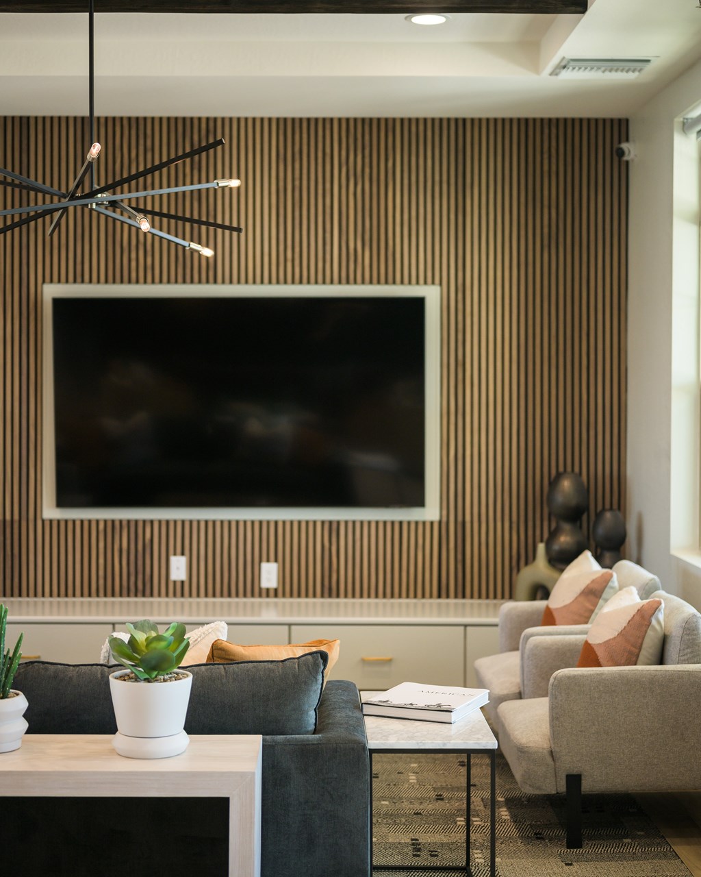 A modern living room with a large TV mounted on a wooden striped wall.