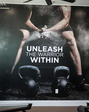 A poster with a man lifting weights and the text "UNLEASH THE WARRIOR WITHIN".
