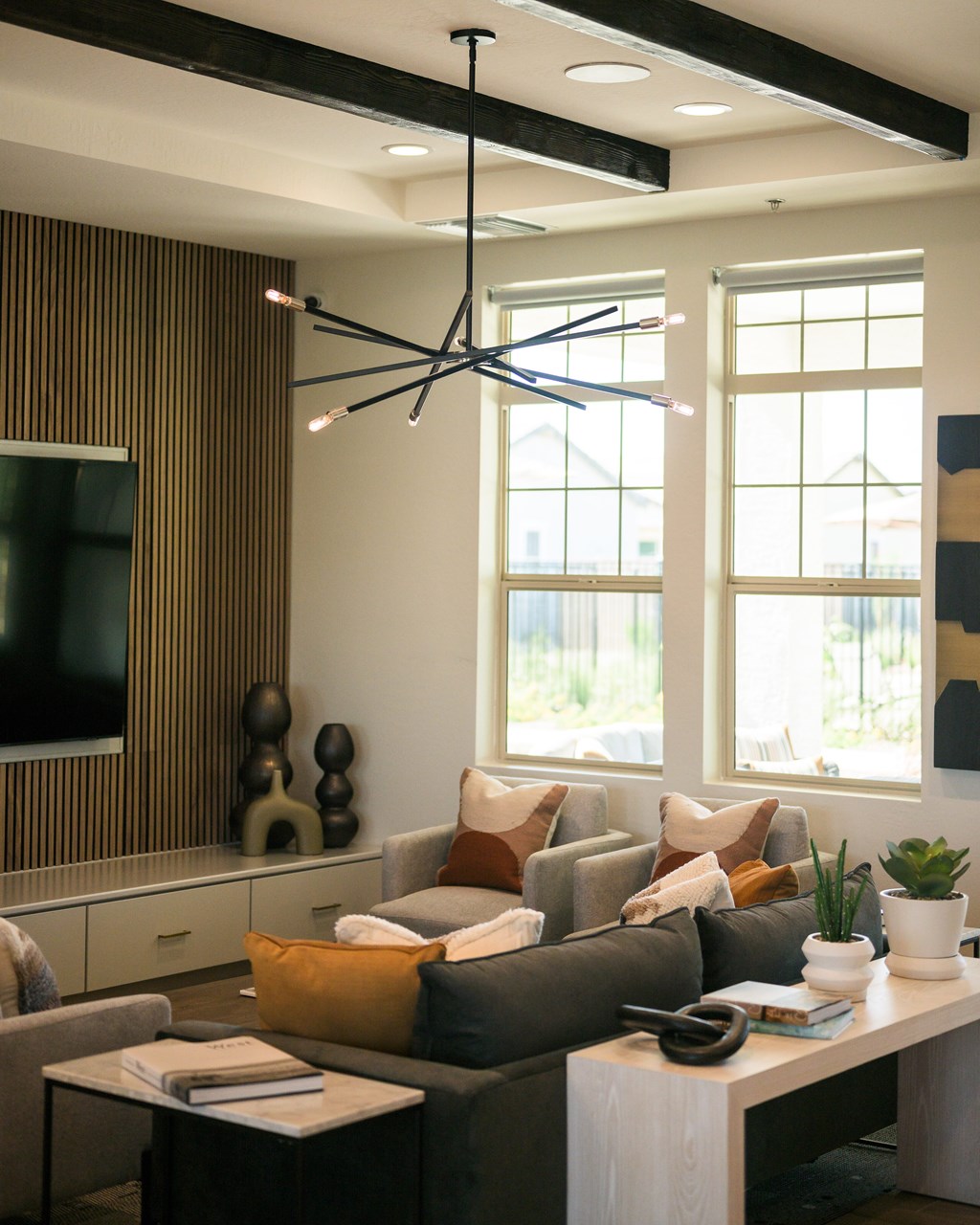 A modern living room with a grey couch, a coffee table, and a large window.