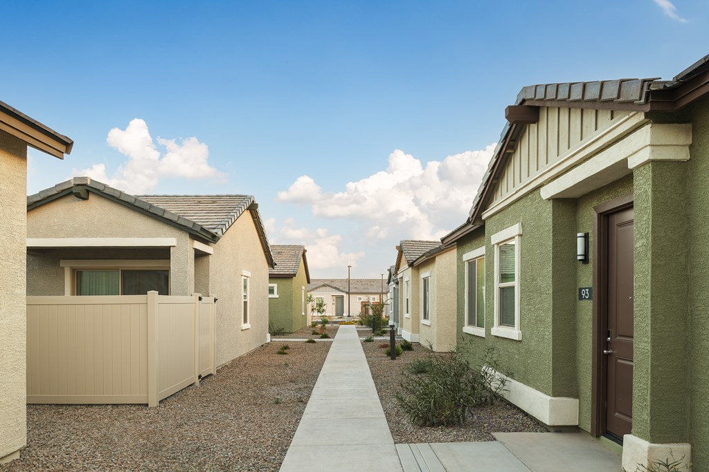 A row of houses with a sidewalk in front.