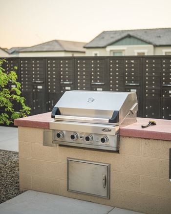 A Weber grill is on a brick patio.