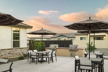 A patio with a table and chairs under umbrellas.