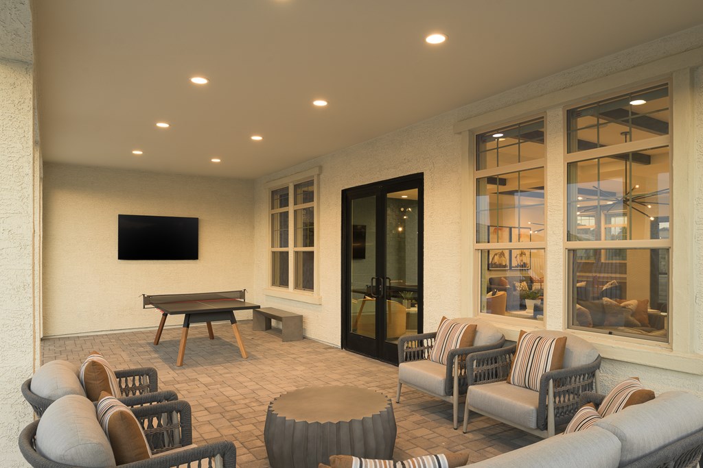 A patio with a table, chairs, and a television.
