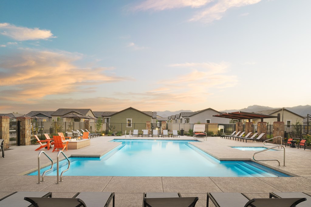 A large swimming pool surrounded by lounge chairs in a residential area.