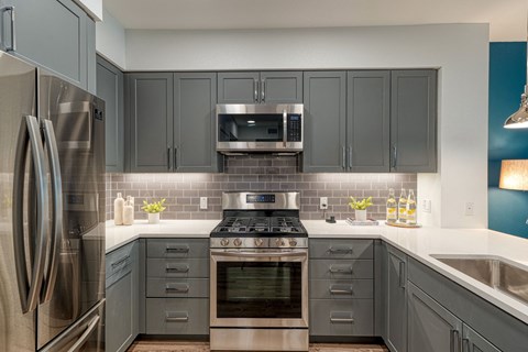 A modern kitchen with a stainless steel refrigerator and a stove top oven.