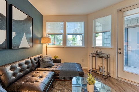 A living room with a brown leather couch and a glass coffee table.