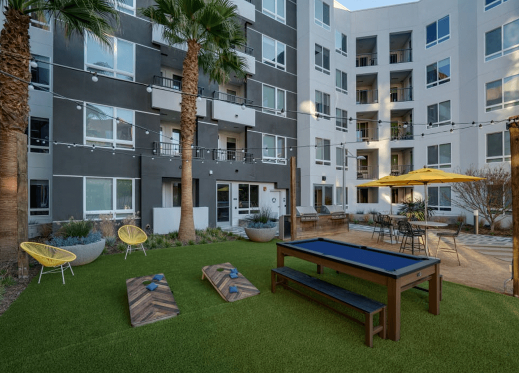 an outdoor lounge area with a ping pong table in front of an apartment building