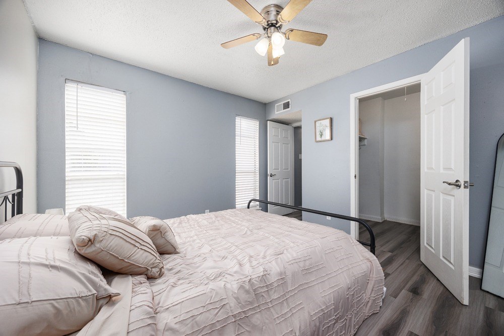 A bedroom with a bed, pillows, and a ceiling fan.