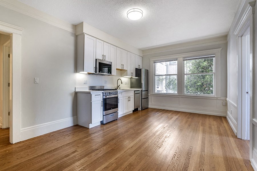 a kitchen and living room with hardwood floors and white cabinets