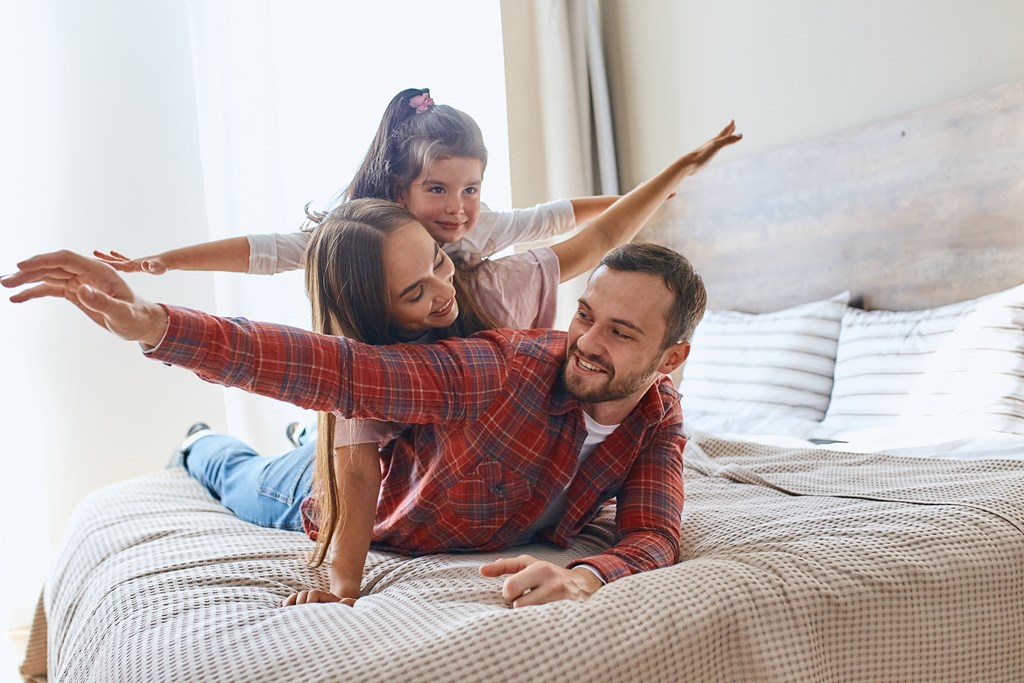 a man and woman laying on a bed with their daughter
