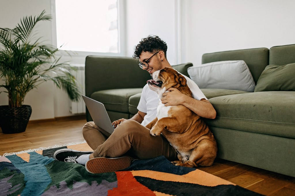 a man sitting on the floor with his dog and laptop