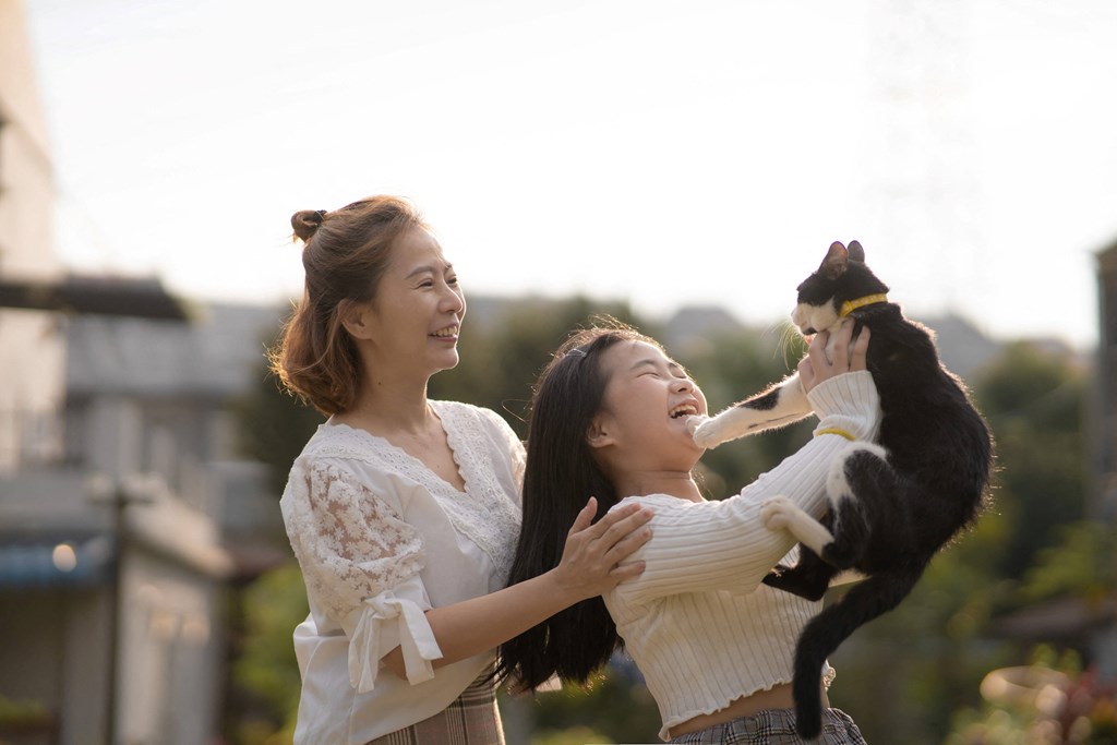 mom and daughter outside holding pet cat