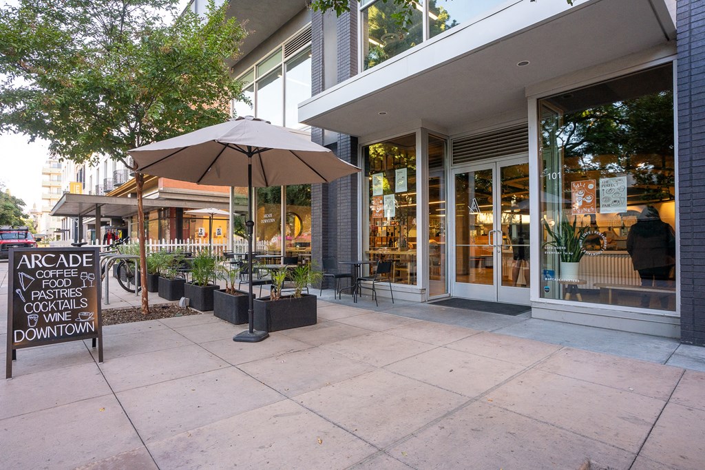 a sidewalk in front of a building with an umbrella and a sign on it at Main+Nine, Riverside
