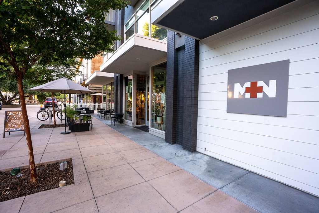 a sidewalk in front of a white building with a nn sign at Main+Nine, Riverside, 92501