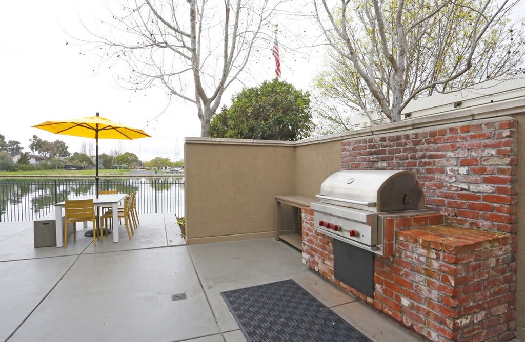 a patio with a grill and a table with an umbrella