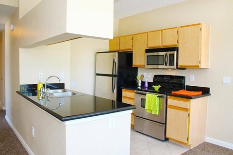 A kitchen with a black counter top and stainless steel appliances.