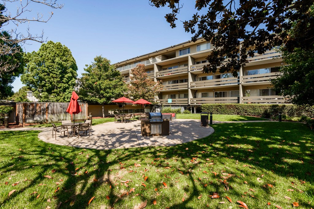 Studio Apartments in Palo Alto, CA - Palo Alto Place - Grill Area with BBQ, Tables, Chairs, Umbrellas, Shade Trees, and Grass.