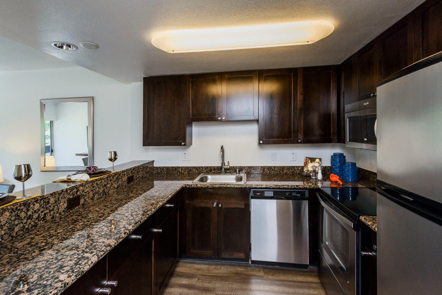 Three Bedroom Apartments in Palo Alto, CA - Palo Alto Place - Kitchen with Brown Cabinets, Granite-Style Countertops, and Stainless Steal Appliances.
