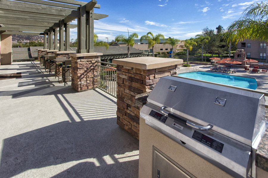 Apartments in Rancho Bernardo, San Diego CA - The Reserve at 4S Ranch - BBQ Deck Overlooking Pool with Grilling Station, Tables, Chairs, and Palm Trees