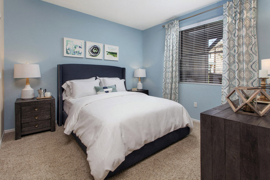 Apartments in Rancho Bernardo, San Diego for Rent - The Reserve at 4S Ranch - Bedroom with Carpeted Floor, Light Blue Walls, Bed, Nightstands, Lamps, Dresser, and Window