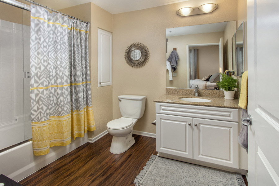 Rancho Bernardo, San Diego, CA, Apartments - The Reserve At 4S Ranch - Bathroom With Hardwood Style Flooring, Recessed Lighting, Large Mirror, Sink With White Cabinets, And Shower With Tub.